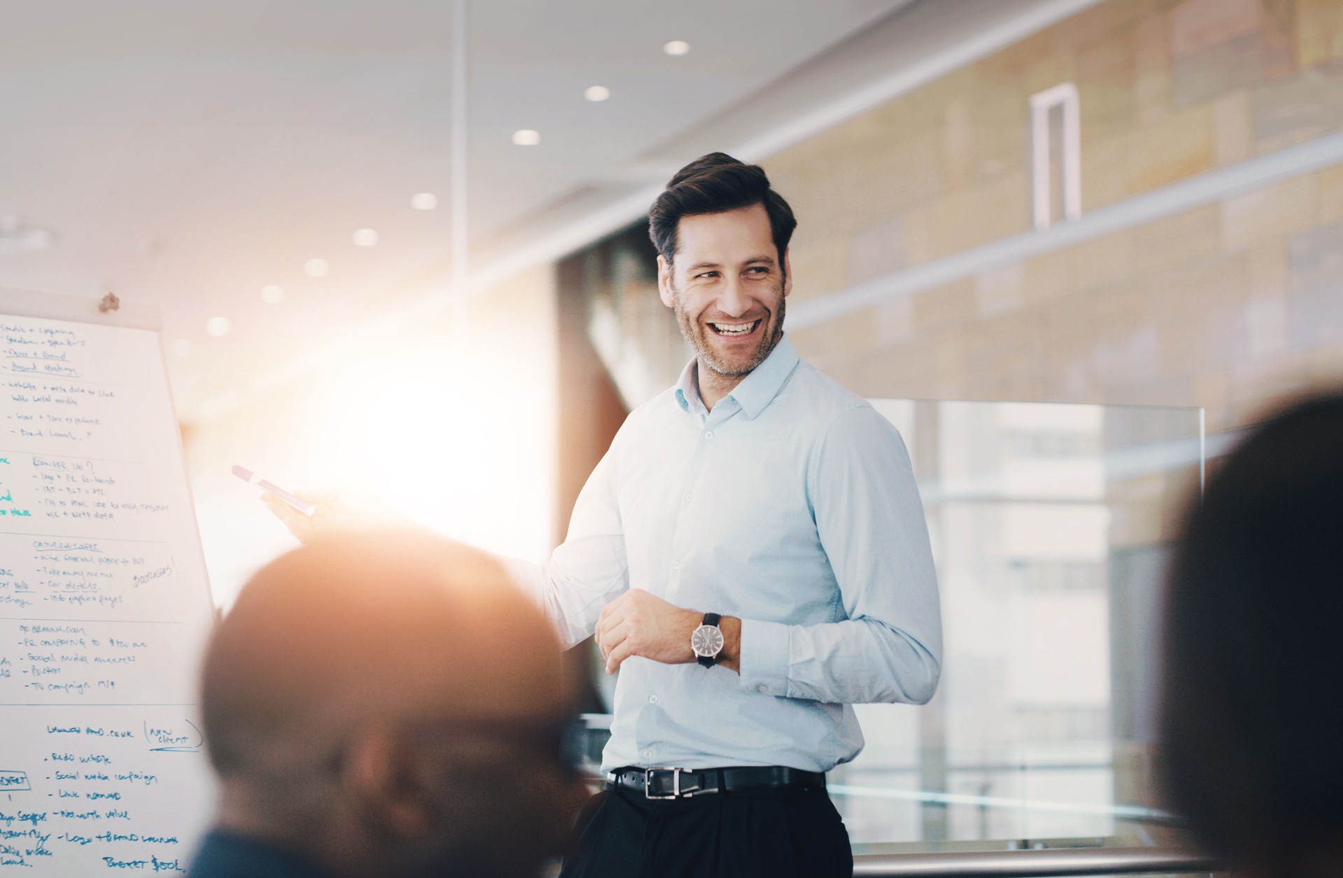 Tableau blanc, présentation et homme d’affaires heureux en réunion pour le coaching, la formation ou la discussion. L’équipe, le leader et le responsable des relations publiques planifient la stratégie d’information sur les campagnes de médias s
