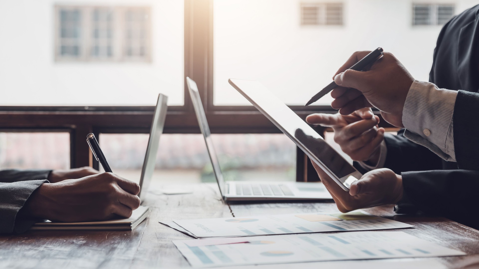 Groupe de gens d’affaires se réunissant, discutant, analysant des graphiques, des données financières, et planifiant un projet de marketing ensemble.