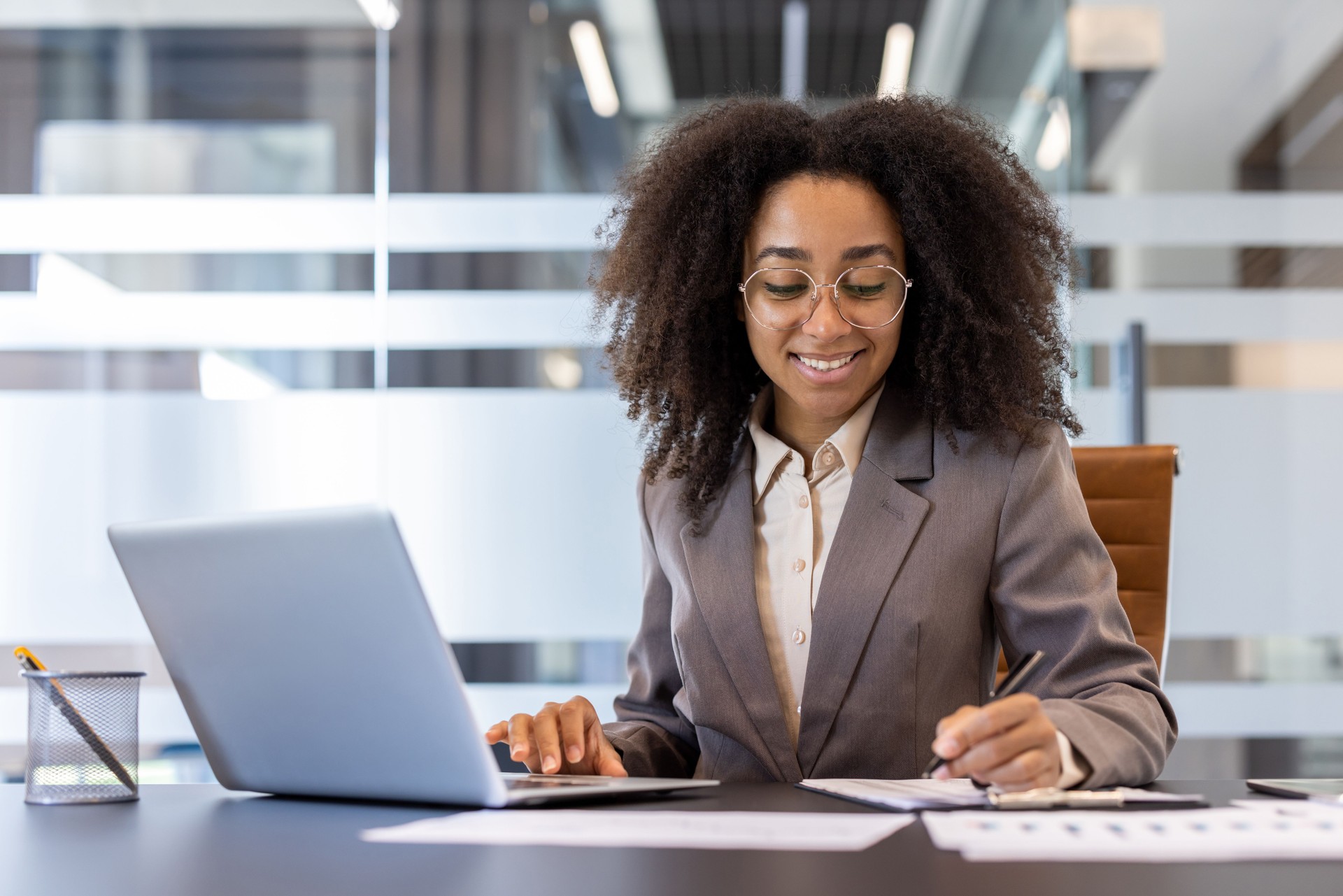 Une jeune femme afro-américaine est assise dans son bureau et travaille avec des documents et des données
